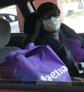 volunteer with food delivery sack, provided by Aetna Insurance, in vehicle on way to the seniors to drop off food